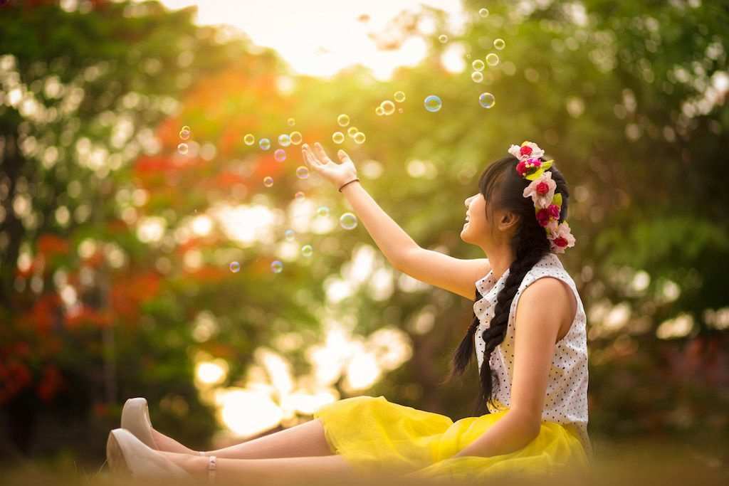 Asian teenager girl in the park under soap bubble rain